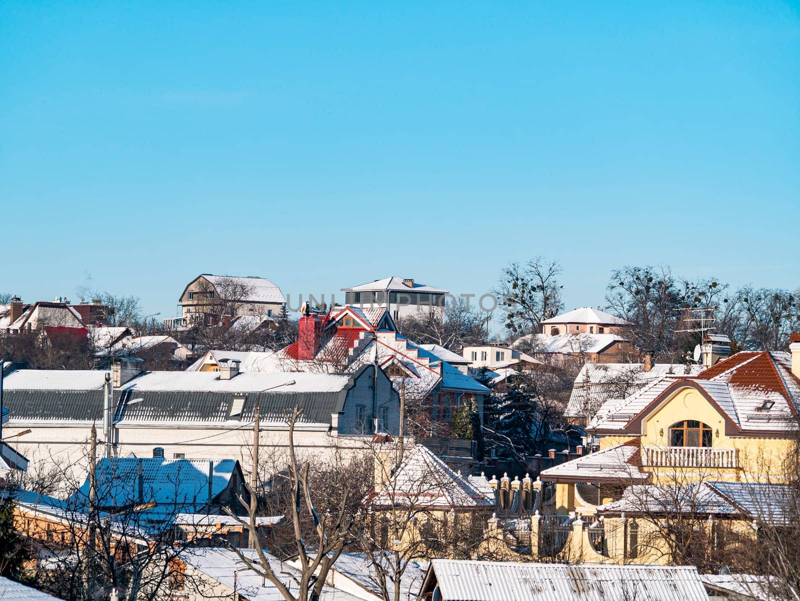 Roofs of houses in the snow against the blue sky. Scenery. Background image. Place for text.