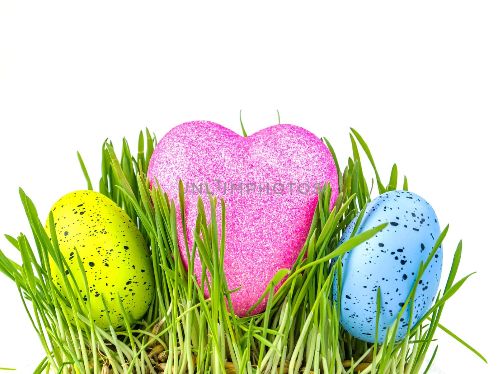 Colored easter egg and heart in green grass on a white background. Easter. Religion. The culture. Place for text. Background image.