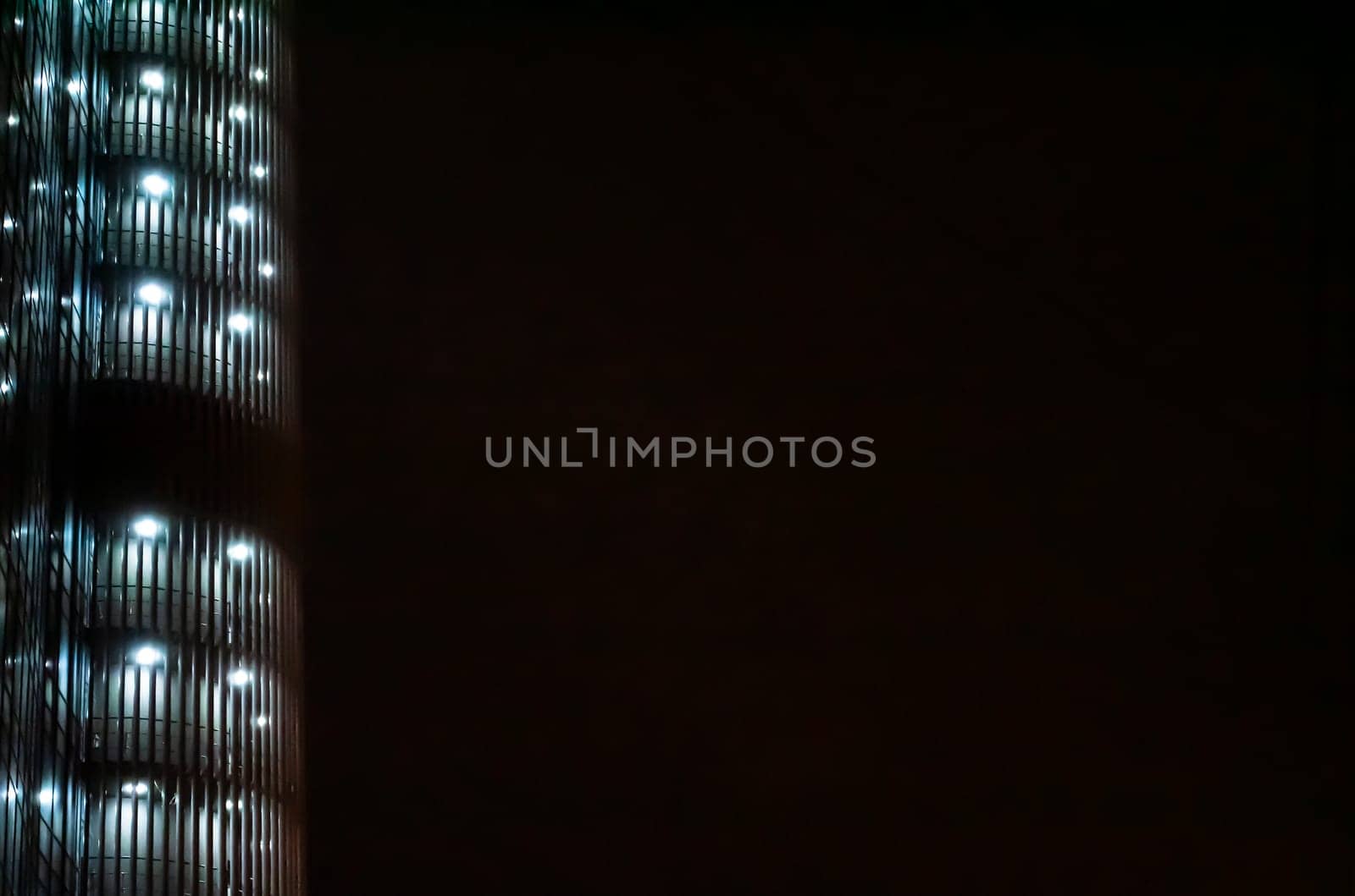 Night illumination of a tall business building. Background image. Place for text. City life.