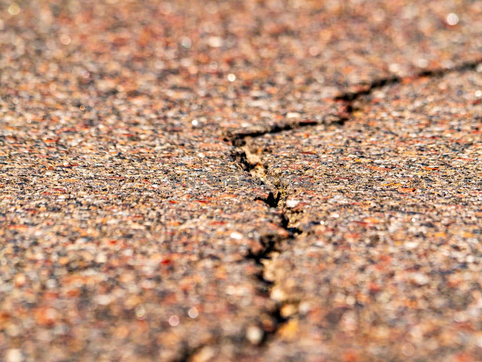 Closeup of a longitudinal crack in the asphalt pavement of a highway. Place for text. Background image. Texture.