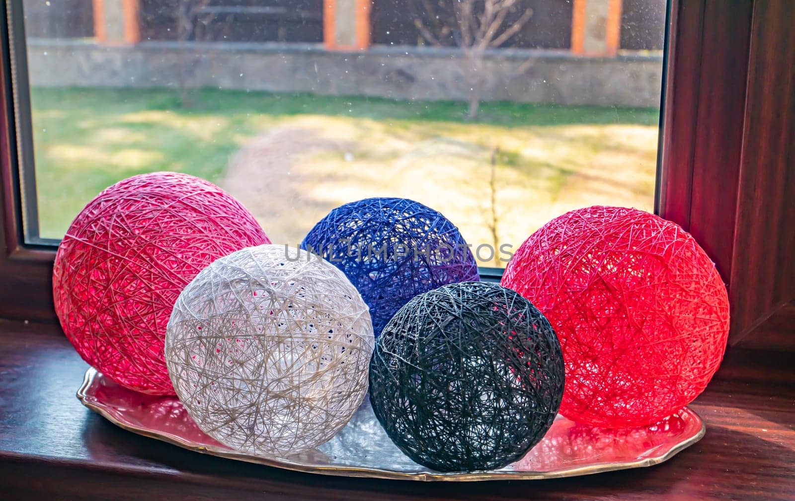 Colored balls of wound thread on a windowsill. Design. Background image. Place for text. Interior.
