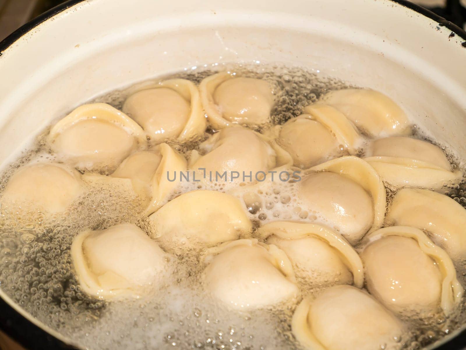 Dumplings from the dough with meat are boiled in boiling water. Food photo. The culinary dish. Ukrainian dumplings. Bay leaf. Dumplings in a plate. Bay leaf. Butter. Menu. Place for text. Poster.