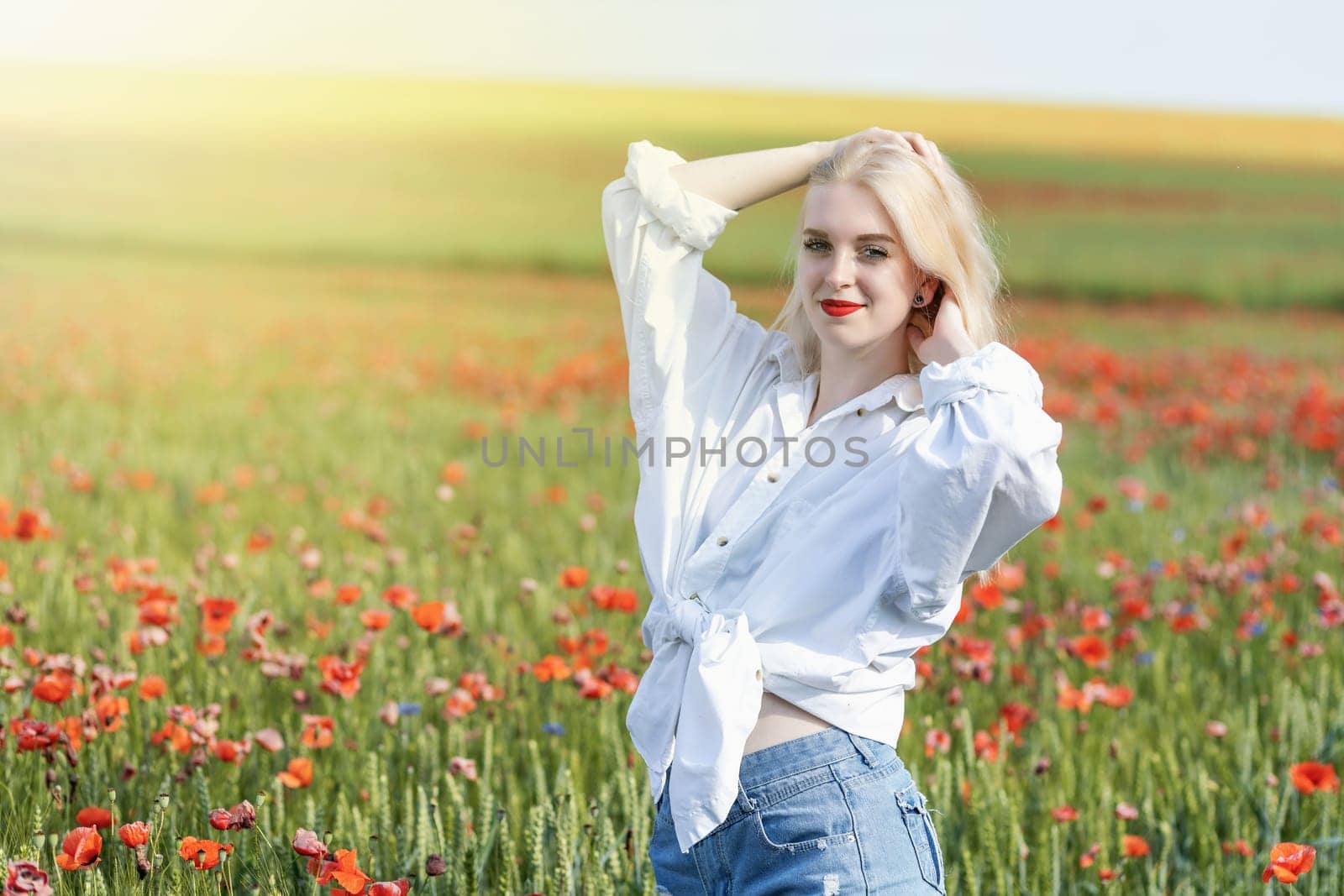 Attractive young girl posing in a field with red poppies. Horizontally.