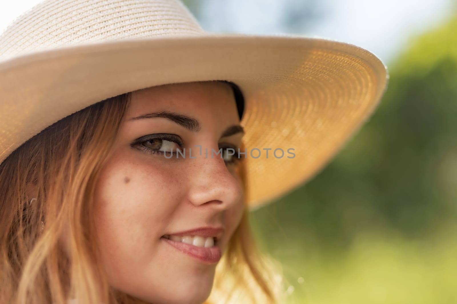Closeup view  of face of the attractive young woman  wearing  straw hat. Horizontally.