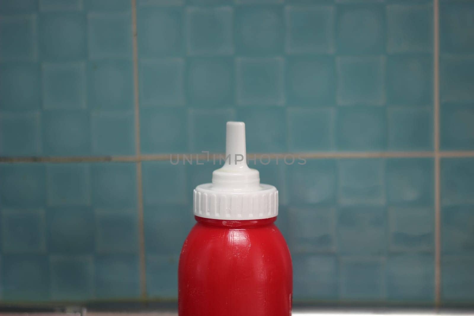 Closeup of red plastic ketchup bottle placed on floor