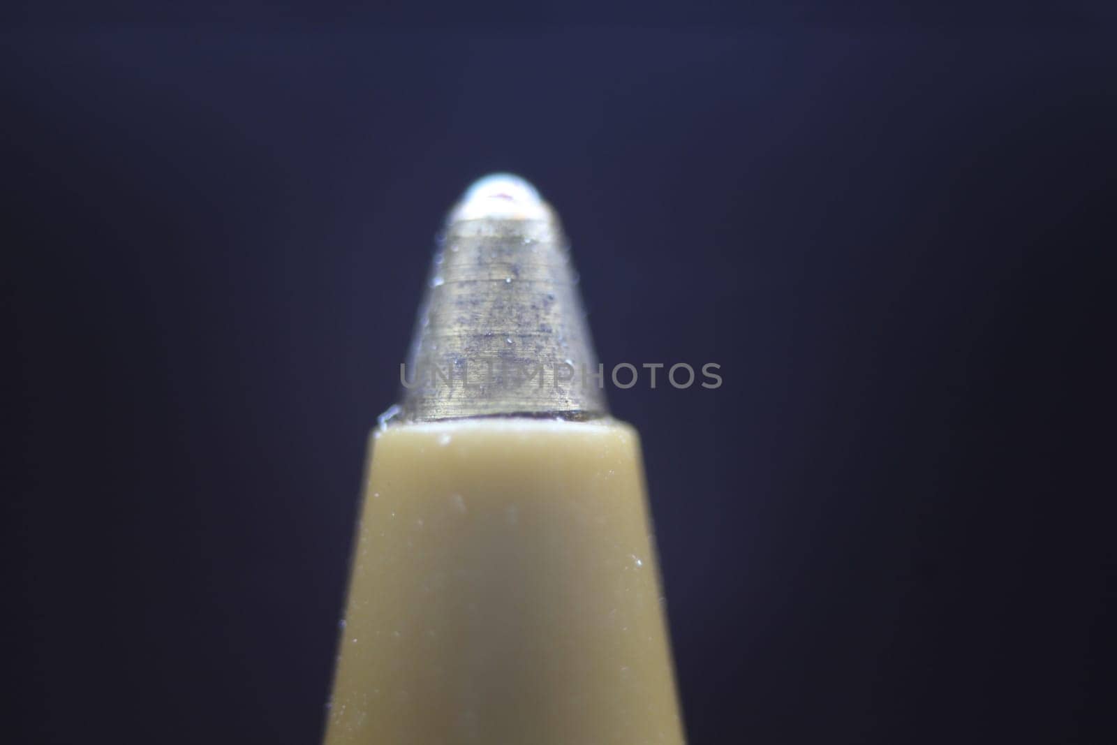Macro photo of ballpoint pen tip with dark grey background. Extreme macro image of metal ballpoint pen on grey background.