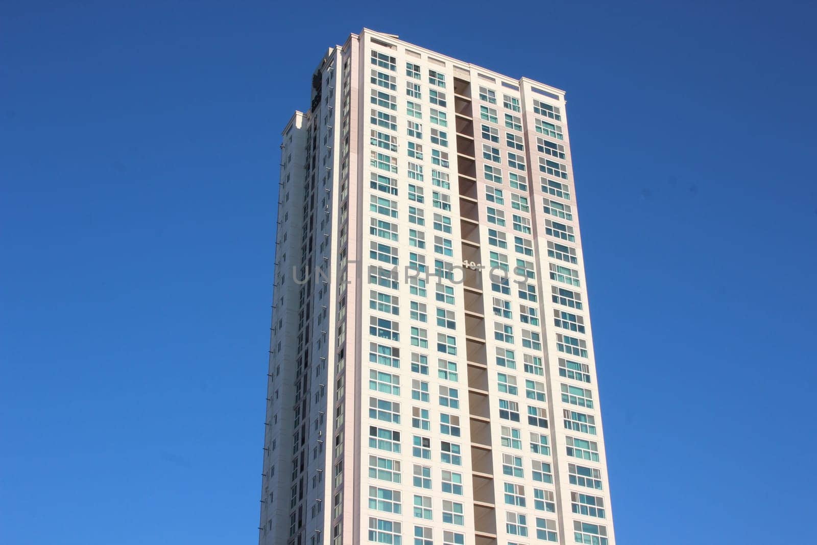 The wide-angle view of a skyscraper commercial building with blue sky on sunny day.