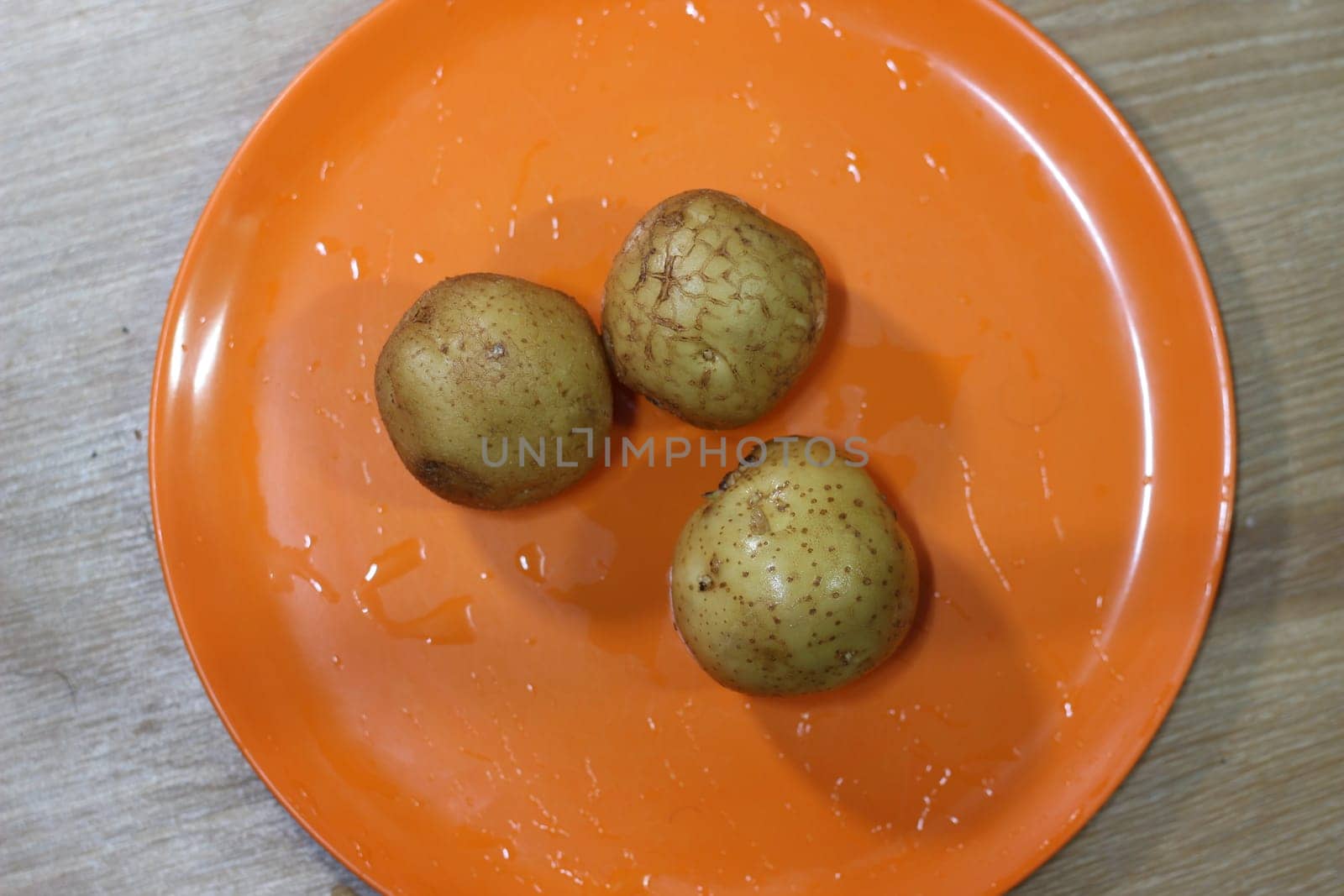 Potato on a orange color cutting board.