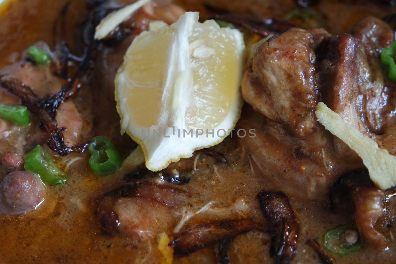Closeup view of traditional Pakistani Haleem dish with salad and Lemon juice.