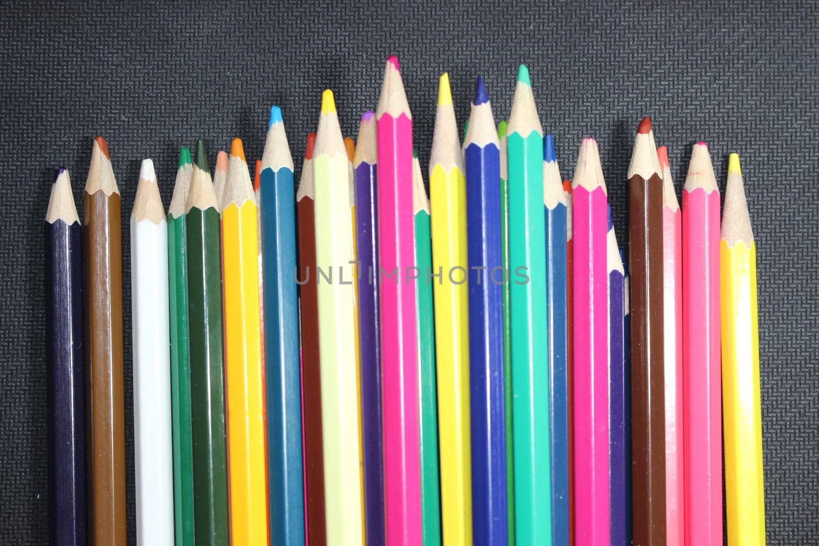 Close-up view of bright colored multicolor pencils on black background
