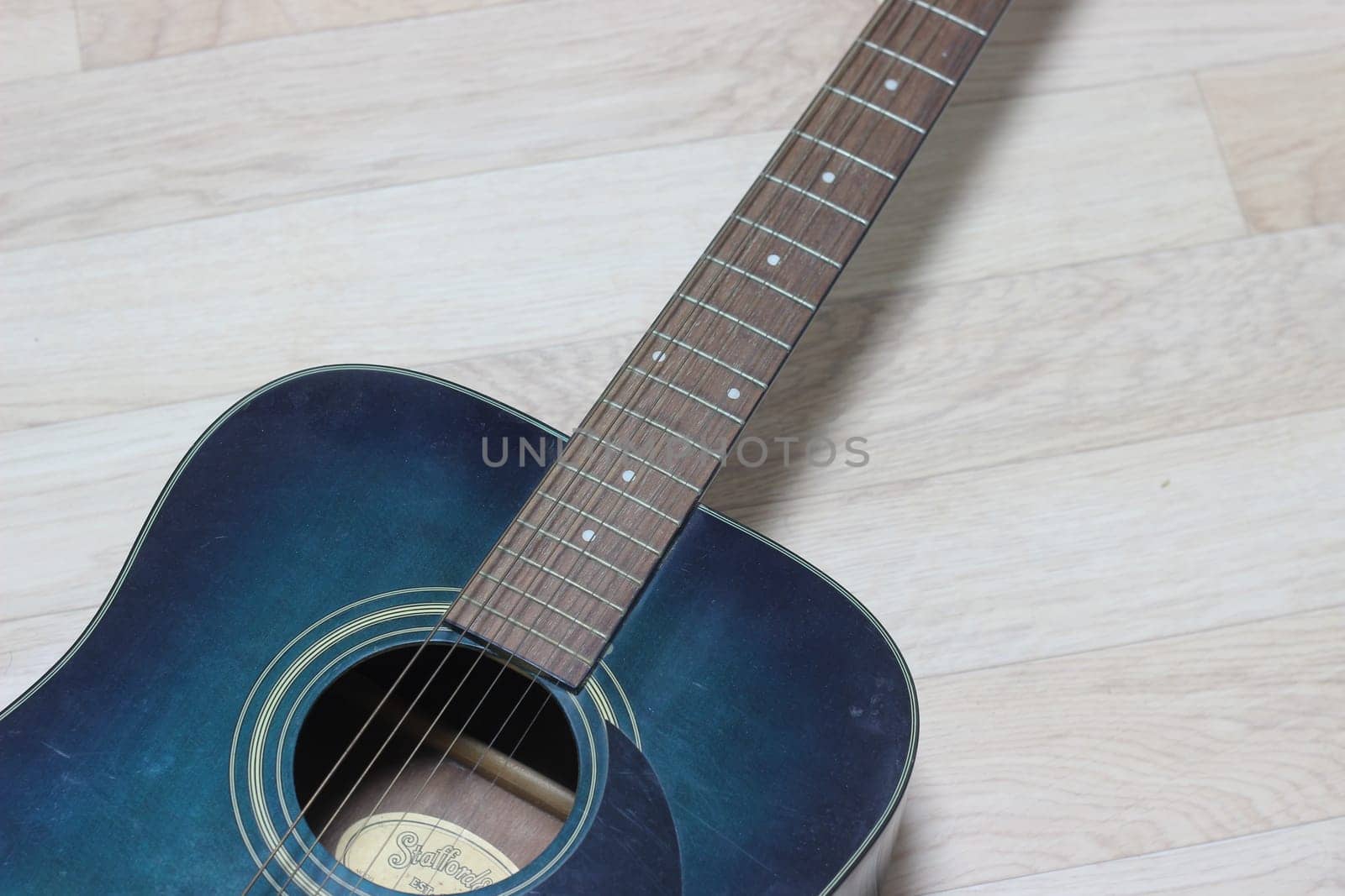 Close up of music guitar. Acoustic guitar with strings on a wooden floor
