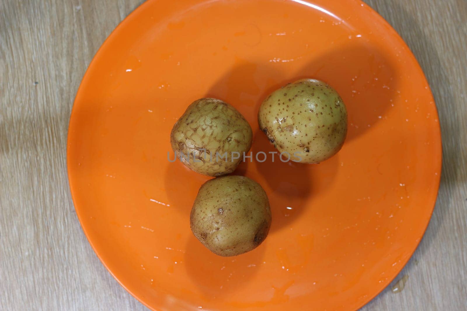 Potato on a orange color cutting board.