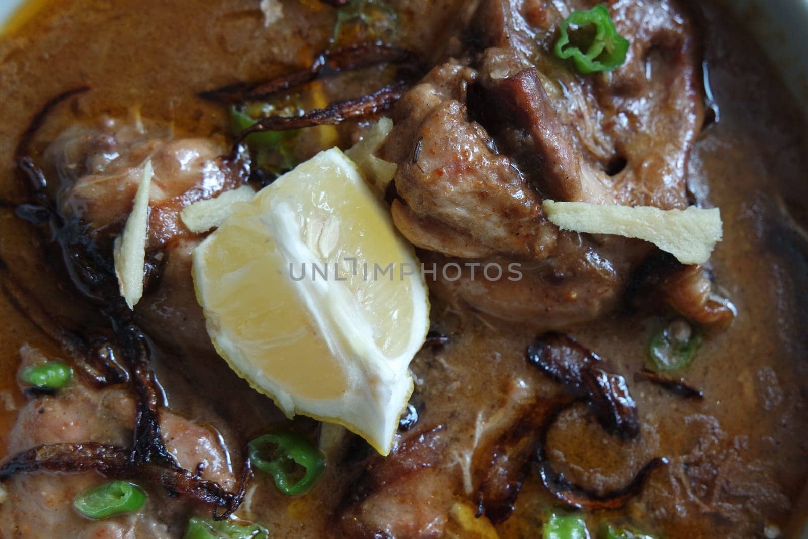Closeup view of traditional Pakistani Haleem dish with salad and Lemon juice.