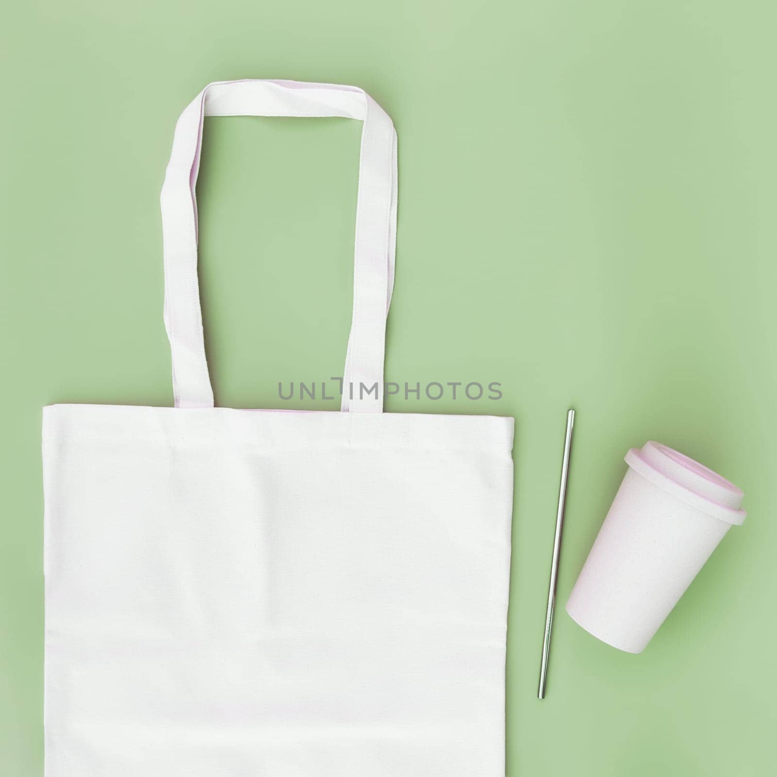Eco white craft paper bag, metal drink straw, coffee cup on green background flat lay with copy space empty advertising area. Mock up for delivery service, reusable and recyclable resources concept