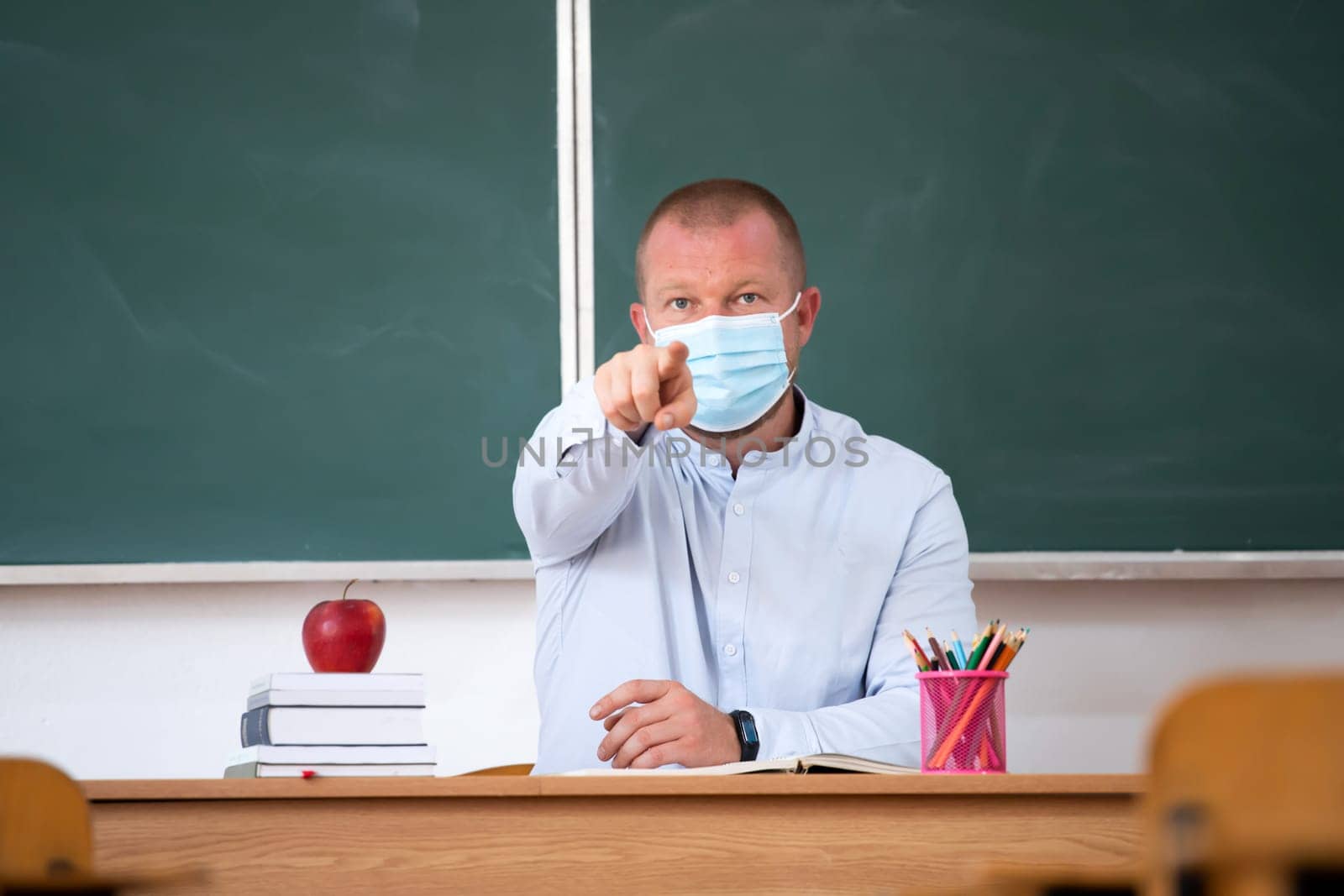 Teacher with mask in the classroom. Social distanting and classroom safety during coronavirus epidemic