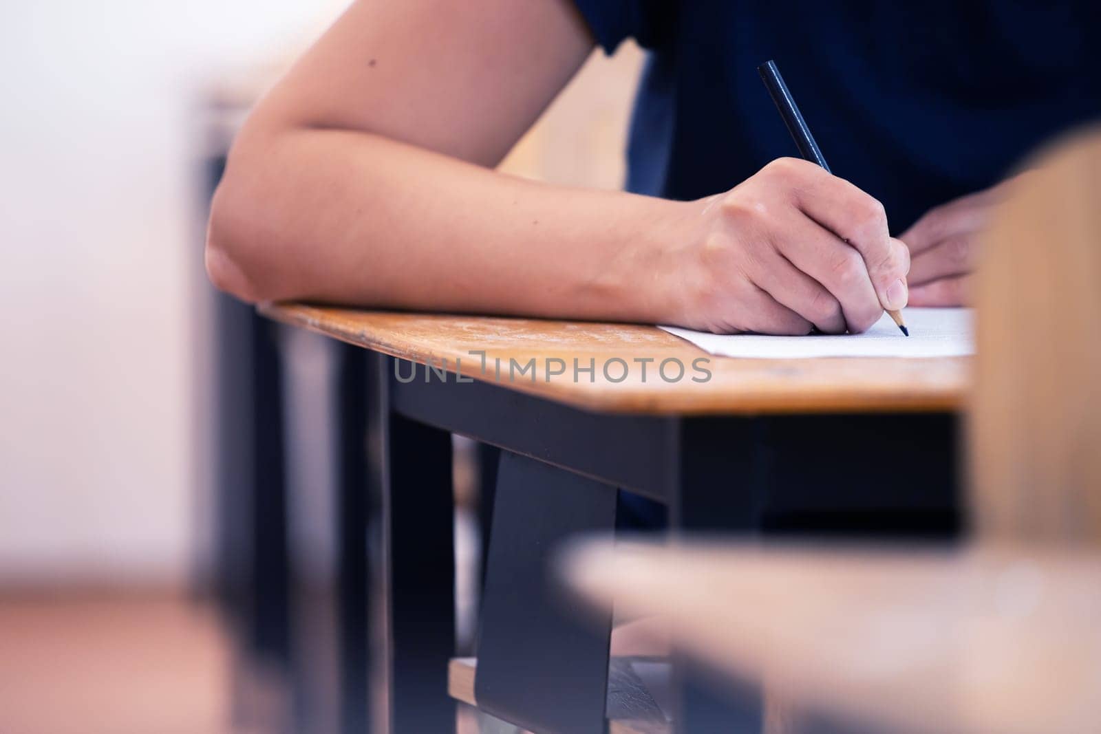 High school or university student holding pencil writing on paper answer sheet. Final exam concept.