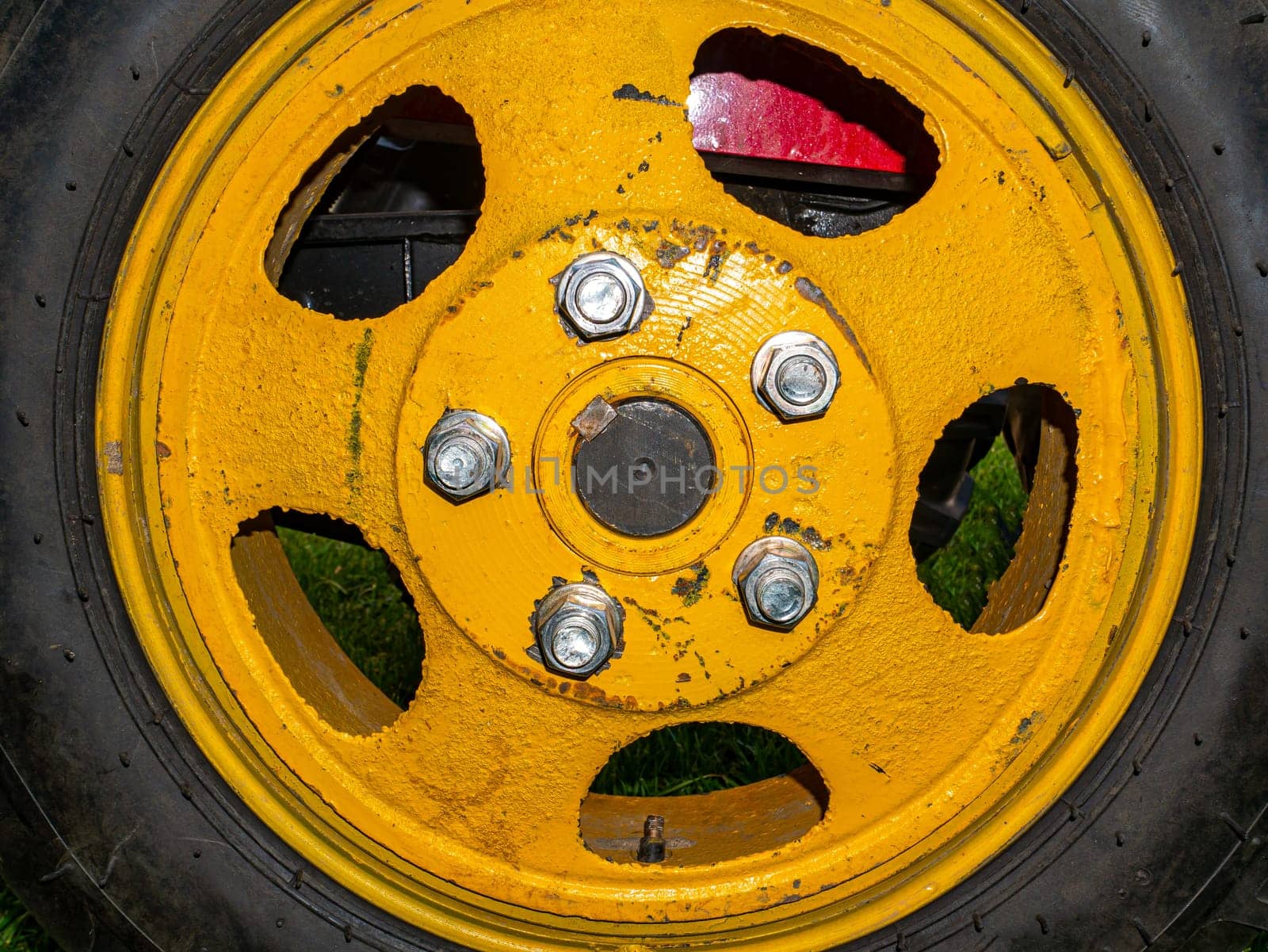 Agricultural tractor wheel with yellow disc on nuts. Fastening the vehicle wheel. Tire service. Rubber tire. Car repair. Car service. Place for your text. Nut bolts. Background image.