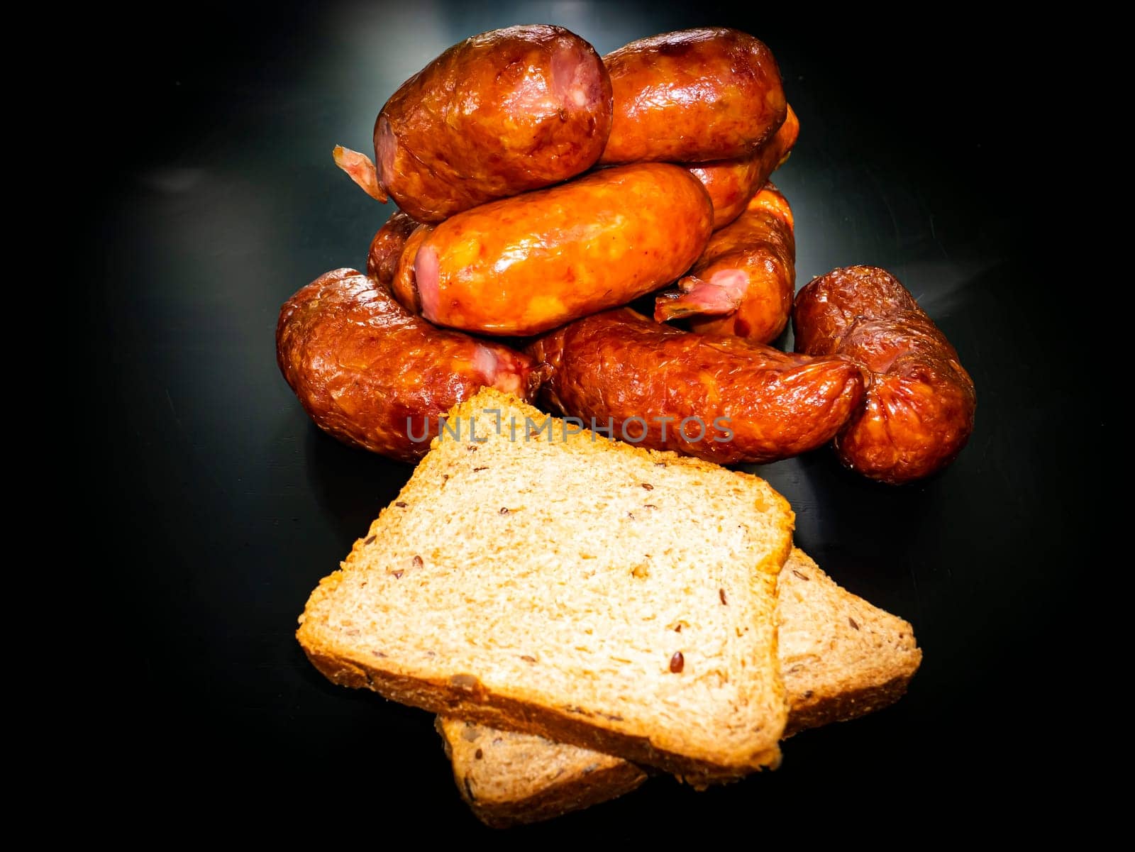 Smoked meat sausages with bread on a black background. Food photo. Recipe. Smoked meat. Fatty food. Home kitchen. Menu of dishes. Advertising photo of the store. Place for text. Poster.