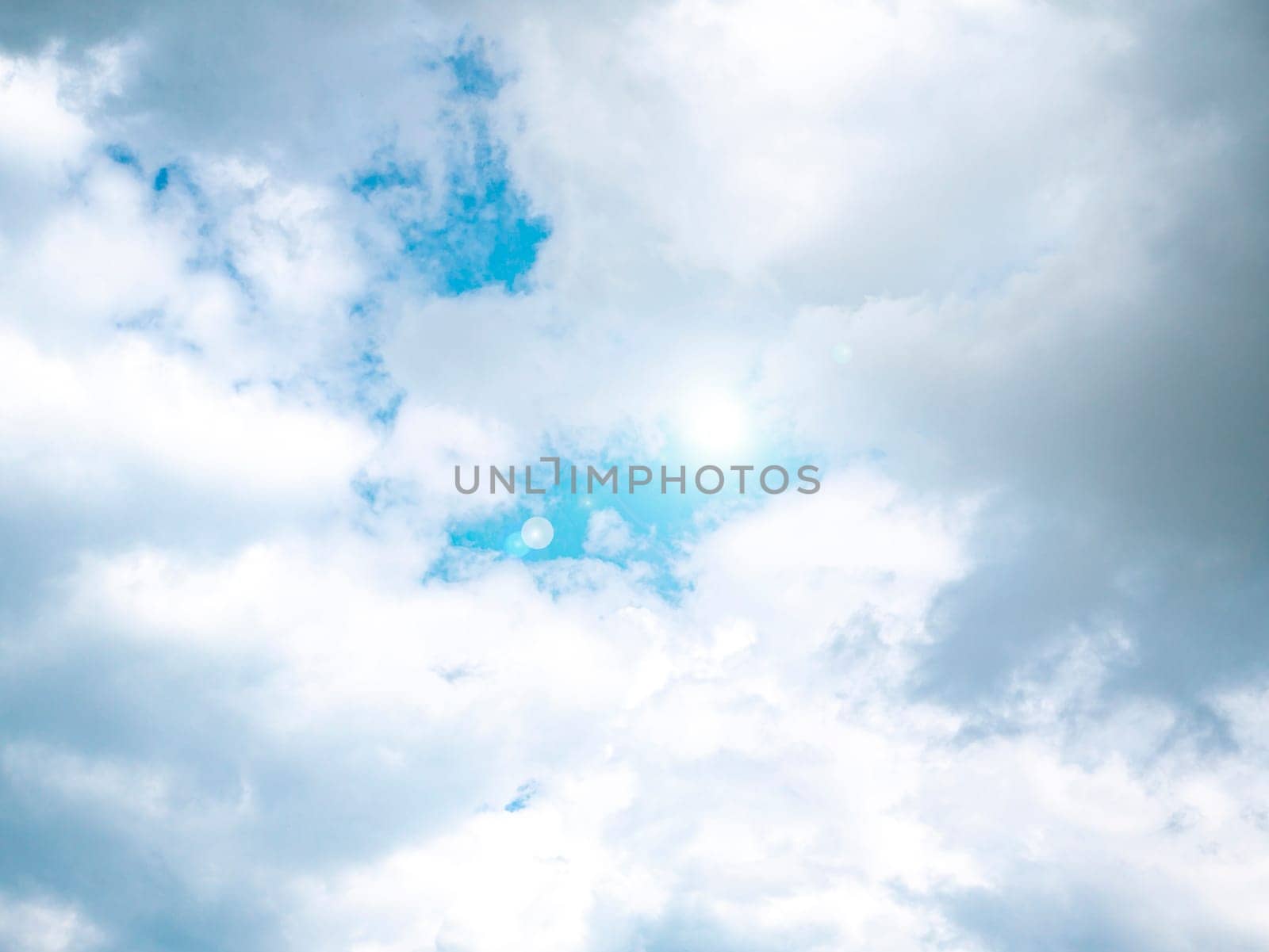 The sun on the background of the cloudy sky. Background image. Sun glare. Camera lens flare. Place for text. Poster. Template. Cloudy landscape. Weather cyclone. Windy weather. Climate change.