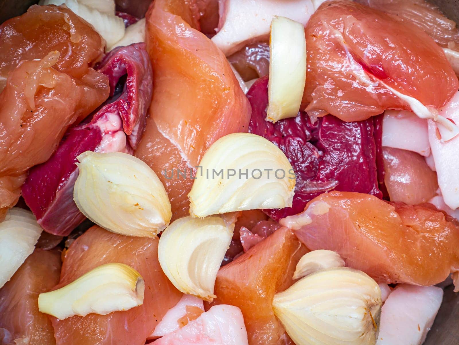 Chunks of raw meat with onions for cooking. Food photo. Meat dish. Preparing food. Cutting meat. Butcher's job. Home kitchen. Recipe. Raw meat. Chicken's meat.