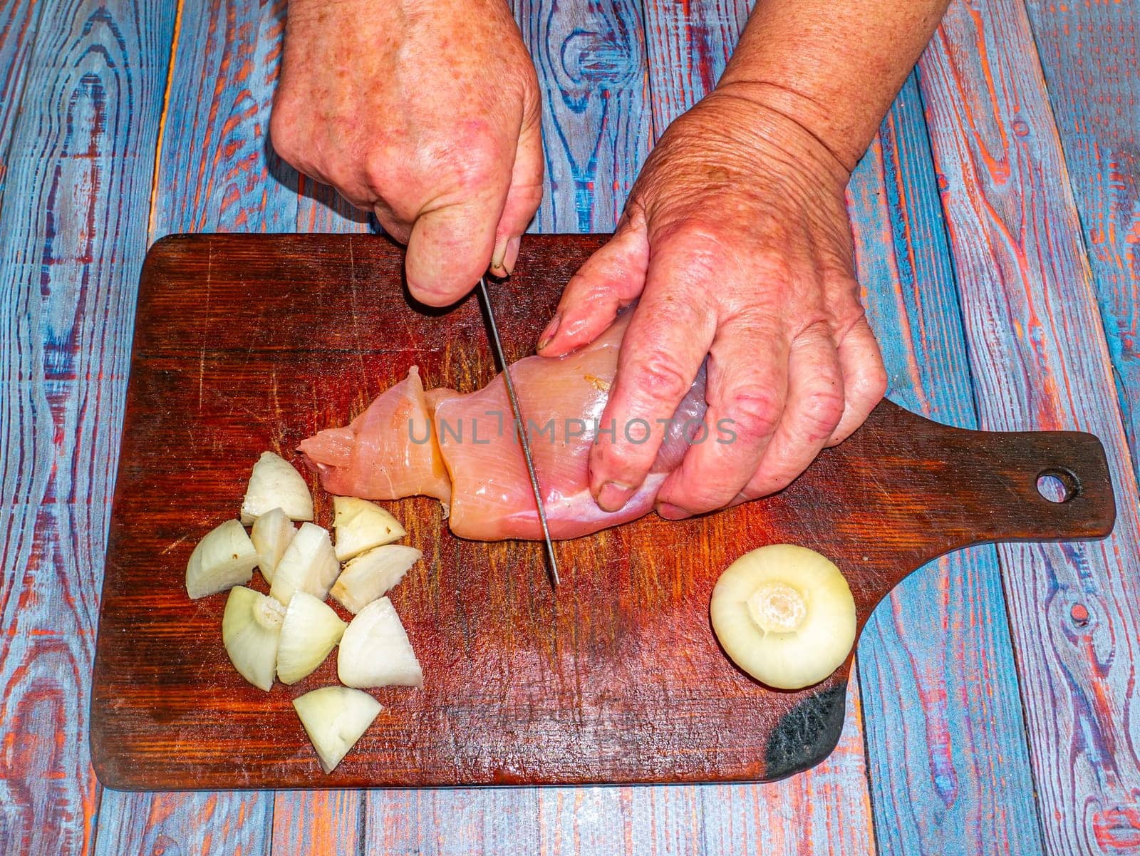 Cutting meat with a kitchen knife for preparing a meat dish. Food photo. Meat dish. Preparing food. Cutting meat. Butcher's job. Home kitchen. Recipe. Raw meat. Chicken's meat. Human hands.