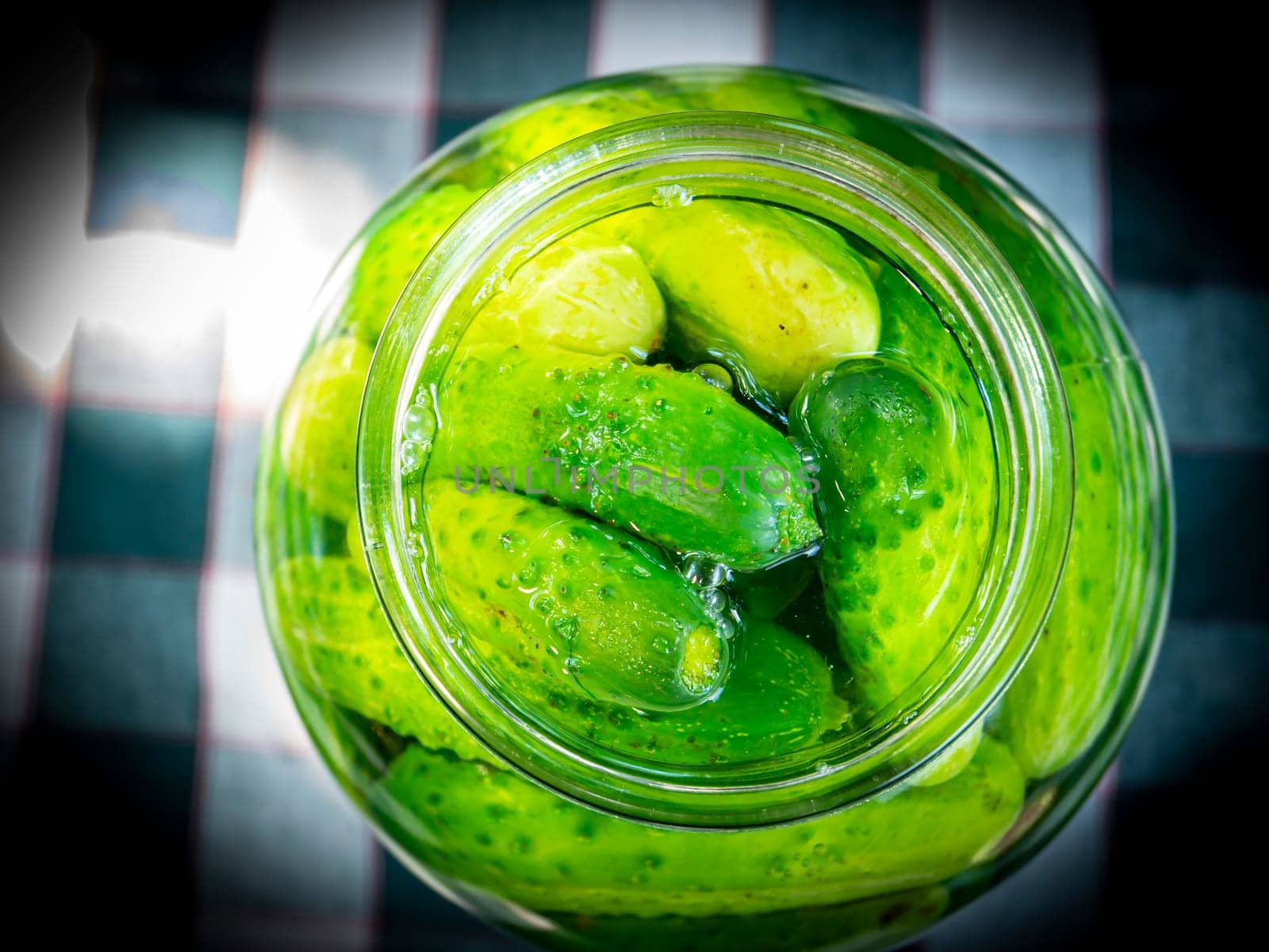 Canned cucumbers in a glass jar on the table. Food photo. Agriculture. Farm. Shop window photo. Preservation of cucumbers. Pickled vegetables.