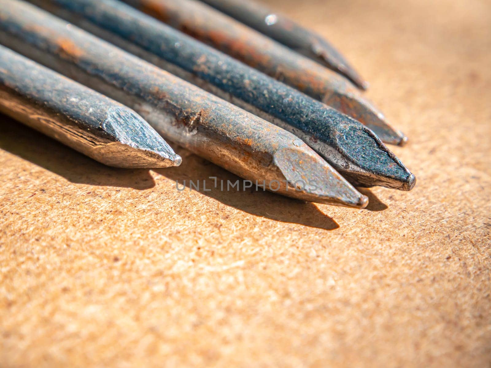 Iron nails on a wooden table macro photo. Nail head. Sharp tip. Joiner's material. Wooden background. Macro photography. Background image. Place for text.