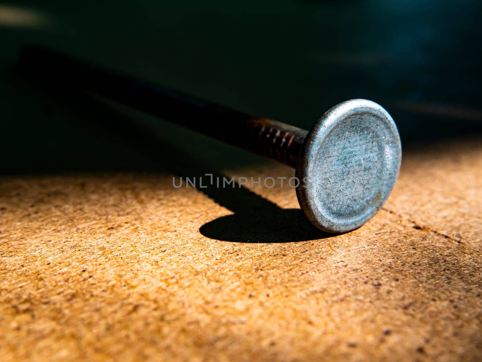 Iron nails on a wooden table macro photo. Nail head. Sharp tip. Joiner's material. Wooden background. Macro photography. Background image. Place for text.