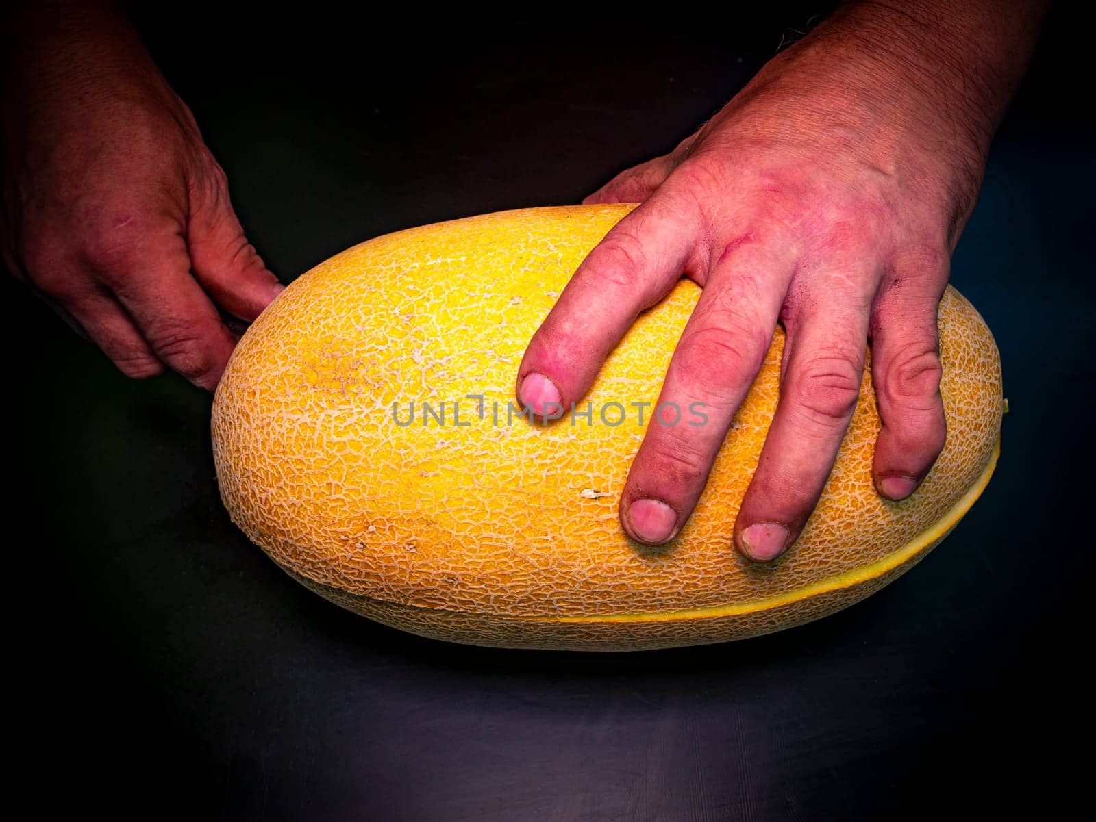 A yellow melon cut with a knife in the hands of a man. Food photo. Melon culture. Agriculture. Place for your text. Black background. Background image. Shchablon. Poster. Vegetarian food.