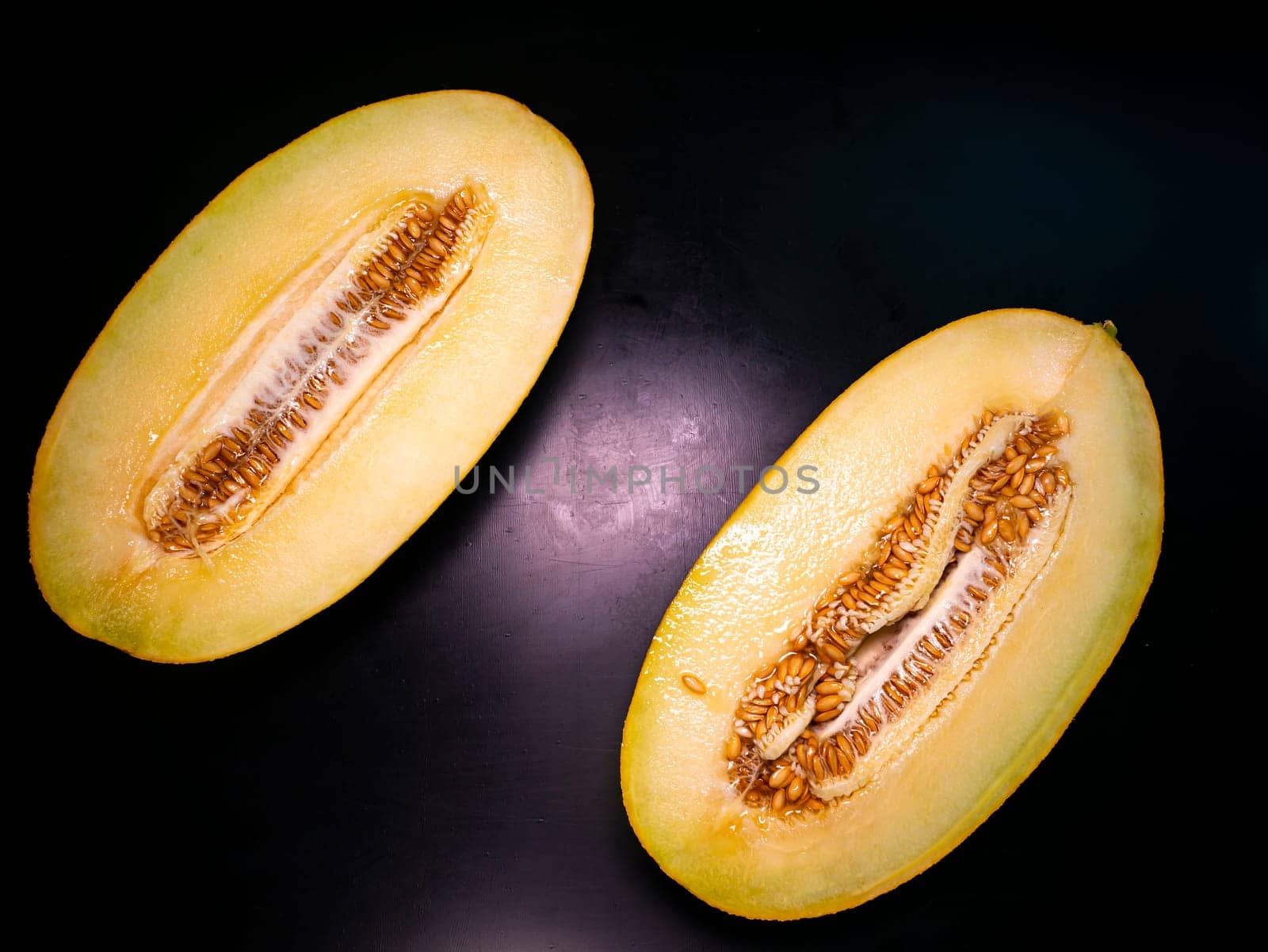 Yellow melon cut with a knife on a black background. Food photo. Melon culture. Agriculture. Place for your text. Black background. Background image. Shchablon. Poster. Vegetarian food.