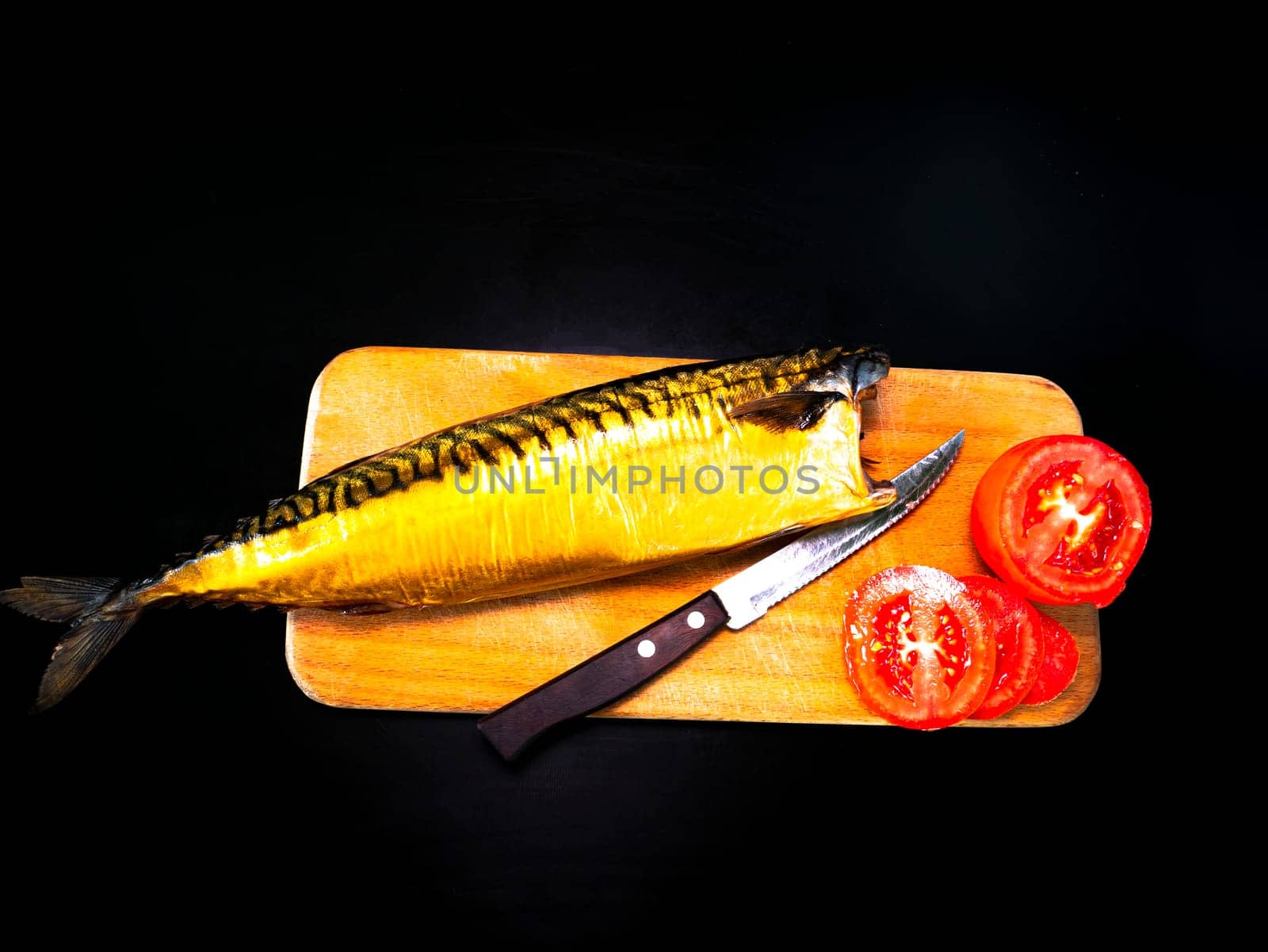 Smoked mackerel fish with tomatoes on a cutting board. Salted mackerel fish. Canned food. Food photo. Recipe. Menu of dishes. Vegetarian food. Home kitchen. Fishing. Black background.