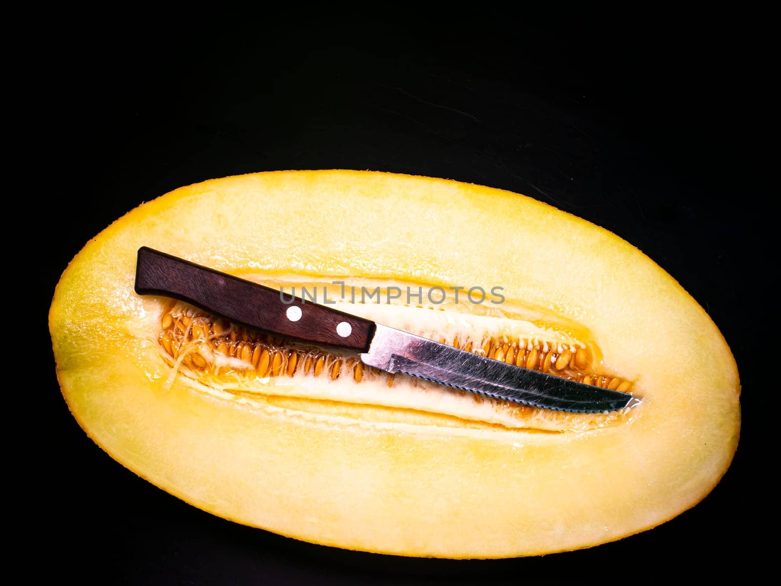 Yellow melon cut with a knife on a black background. Food photo. Melon culture. Agriculture. Place for your text. Black background. Background image. Shchablon. Poster. Vegetarian food.