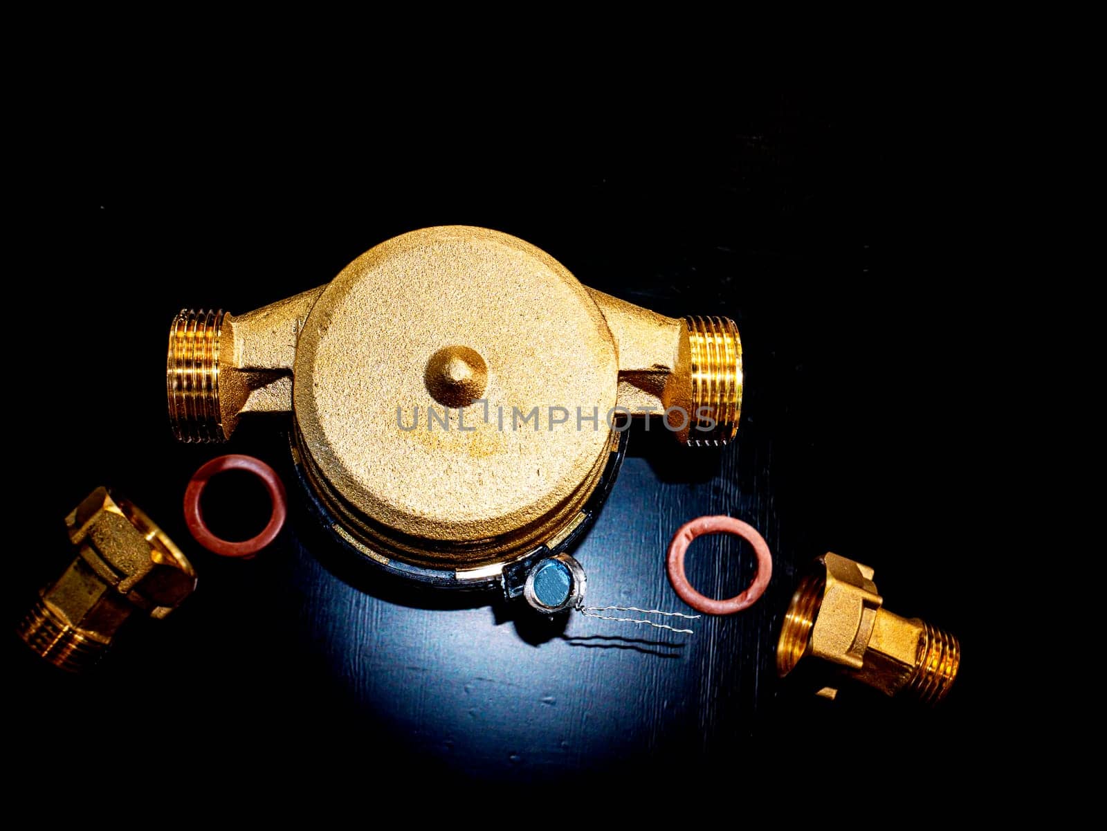 Water meter with threaded connection for nuts. Black background. Plumbing equipment. Plumbing repair. Plumbing repairman. Pipeline. Background image. Place for your text.