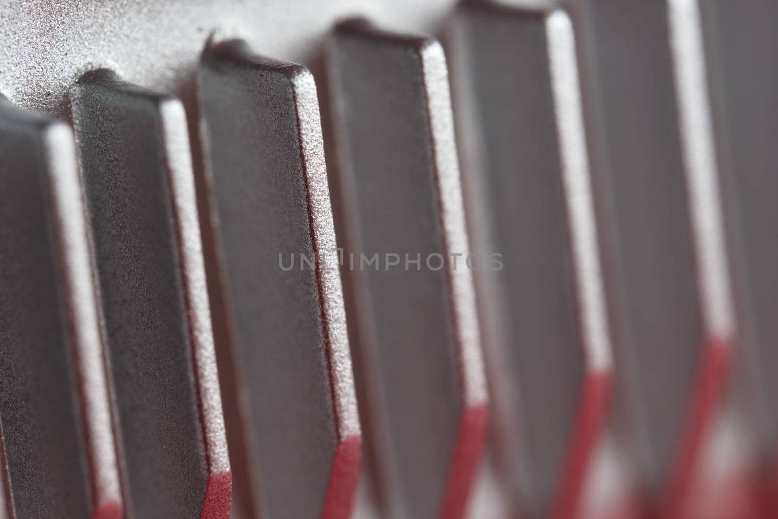 Aluminium or Aluminum heat sink cooling fins. Full frame super macro close up, showing metal detail and coarse finish. Red and silver color theme.