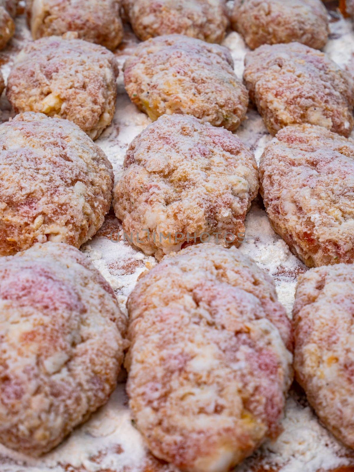 Meat cutlets sprinkled with white flour on the kitchen table. Culinary recipe for meat cutlets. Cooking food. Home kitchen. Menu of dishes. Cutting board. Background image.