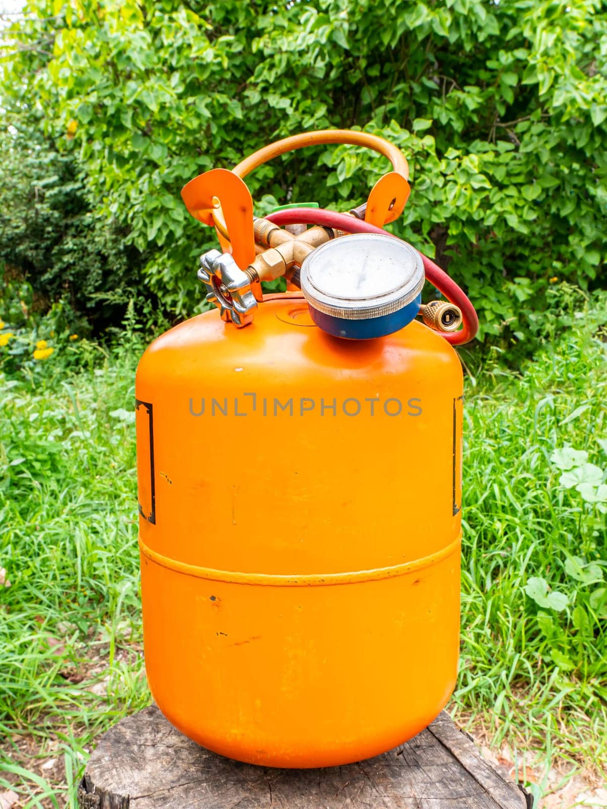 Refrigerant cylinder and hoses with pressure gauge. Orange bottle with freon. Pressure gauge for the repair of refrigerators and air conditioners. Refrigerator and air conditioner repair tool.