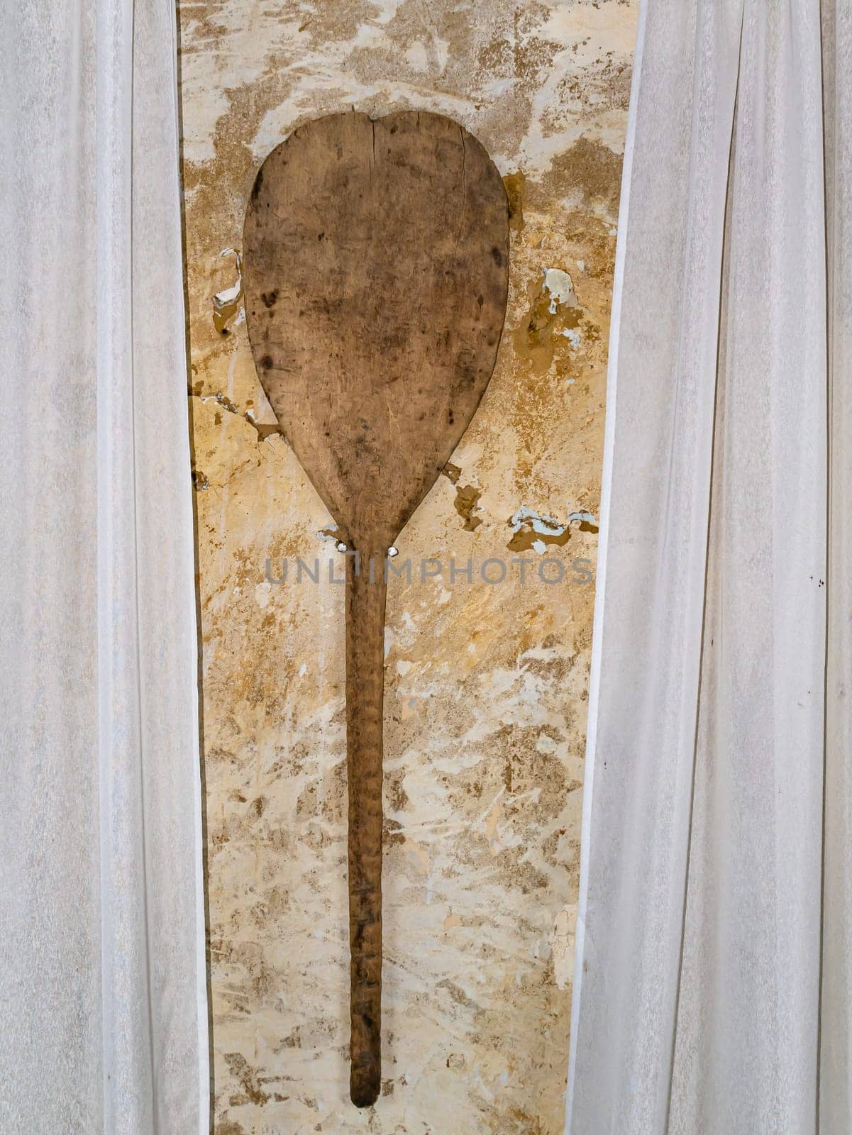 Old wooden shovel for baking bread in the oven. Wooden kitchen tool. Retro room interior. Old-fashioned background. Background image. Place for text.