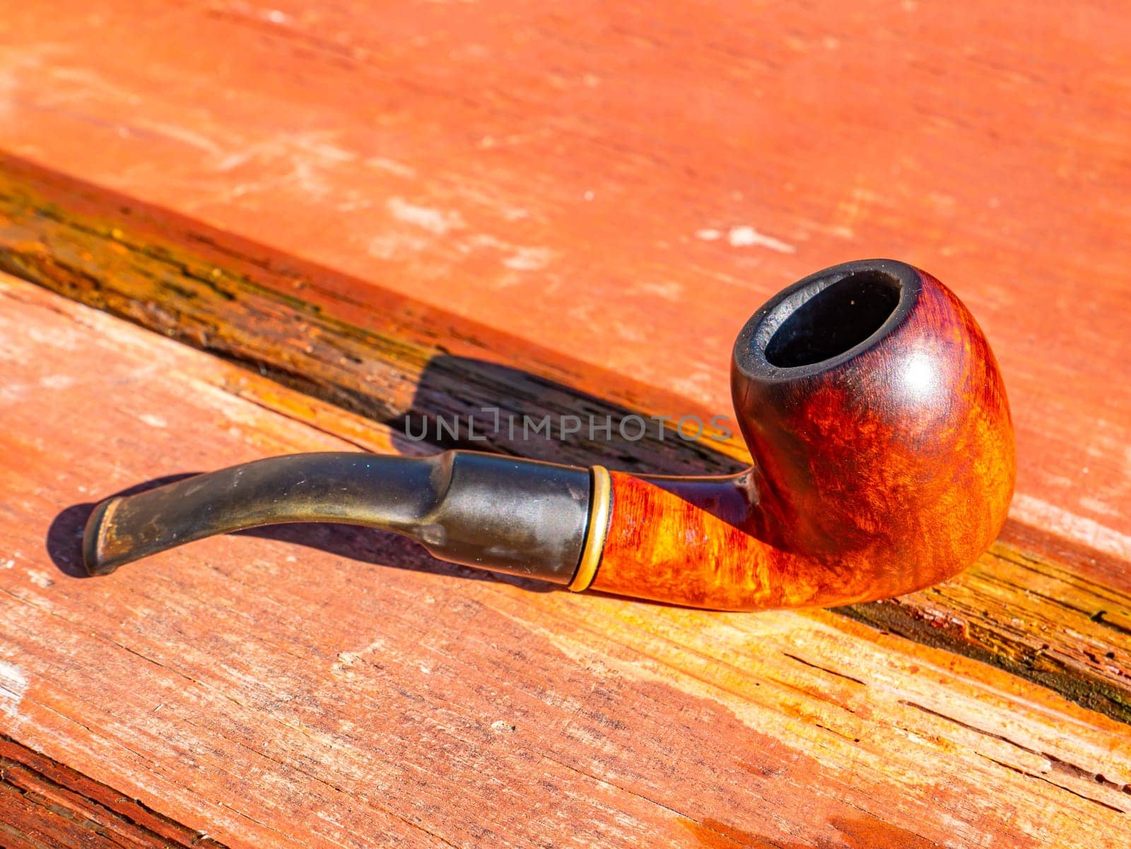 Wooden smoking pipe for tobacco on the table. Pipe for smoking tobacco. Smoker's tool. Wooden table. Bad habits. Nicotine addiction. Nicotine in cigarettes. Background image. Poster.