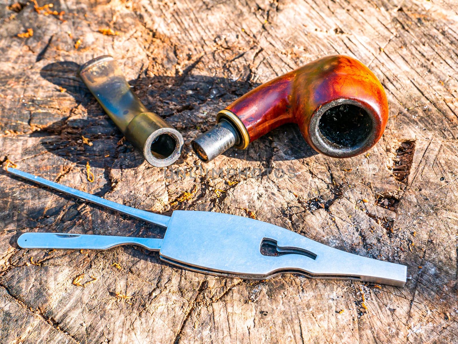 Tool for cleaning the smoking pipe from tobacco. Smoking pipe care. Smoker's tool. Human hand. Bad habits. Nicotine addiction. Nicotine in cigarettes. Background. Place for your text.