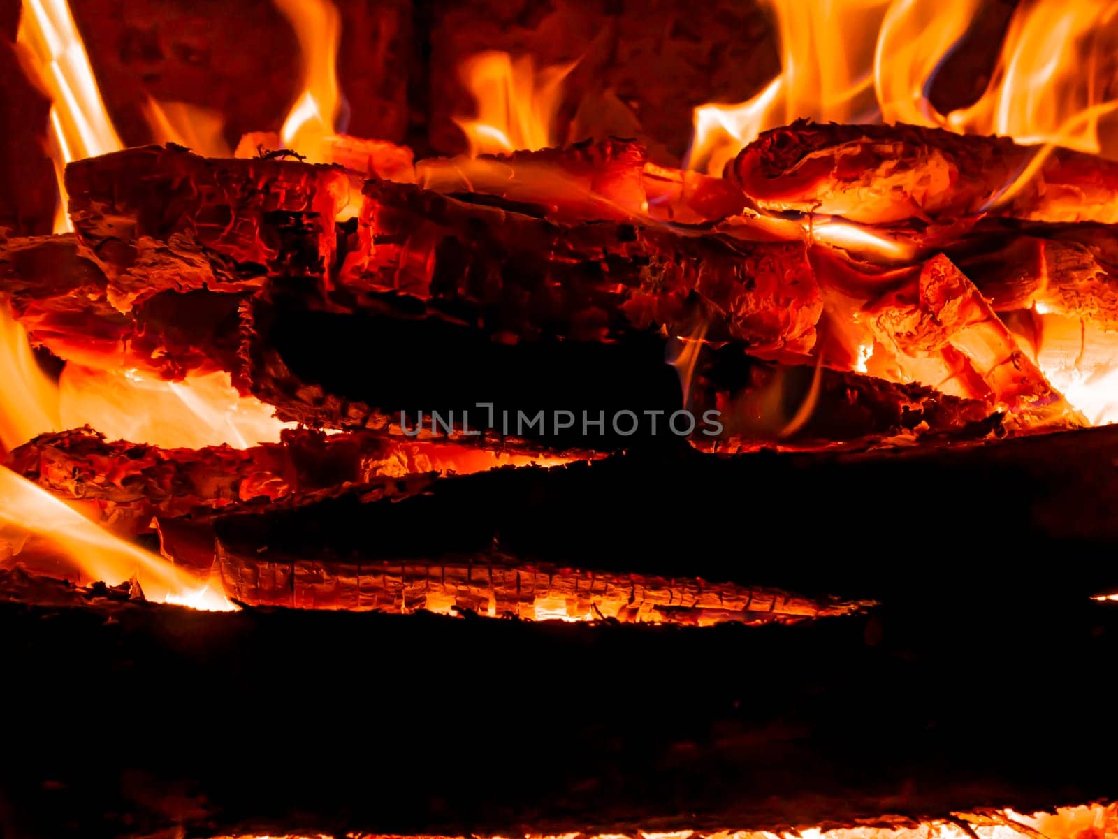 Red flame of fire in a wood stove. Fire sparks. Bright flame of a bonfire in the night. Fiery sparks above the wood. Fiery smoke. Heat in the furnace. Background image. Firefighter. Danger of arson.