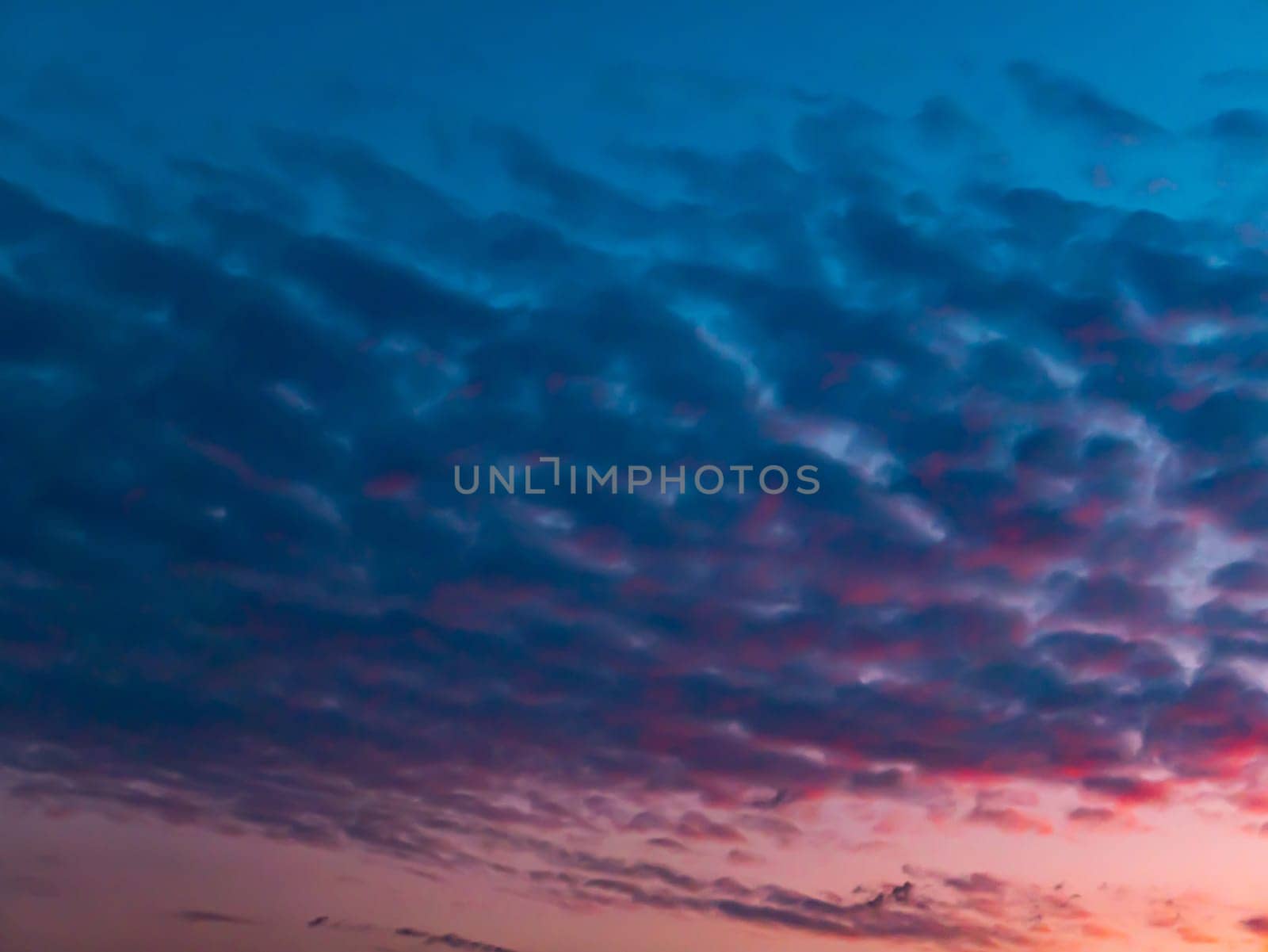 Red sunset on a cloudy blue sky with clouds. Pink evening dawn. Morning red pink sunshine dawn. Clouds in the blue sky. Pink morning dawn. Heavenly landscape. Space. Stratosphere.