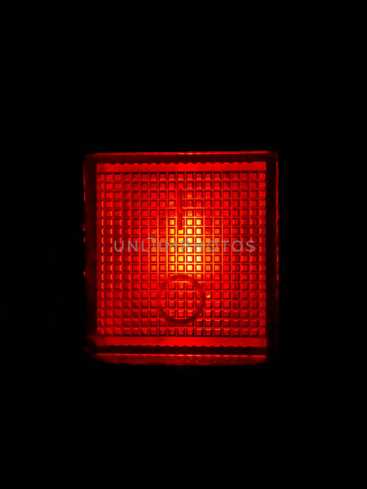 Glowing red plastic lamp in the dark. Signal light red. Night illumination. Black background. Electrical appliance button. Emergency lighting. Electric light. Background image.