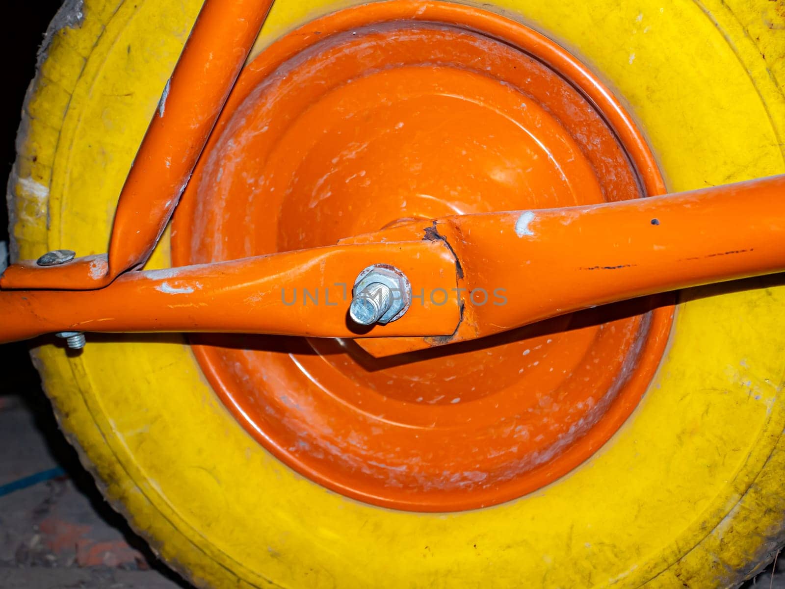 A yellow wheel with an orange disc of a garden wheelbarrow. Yellow rubber wheel tire. Vehicle. Tire service. Background image. Place for your text. Poster.