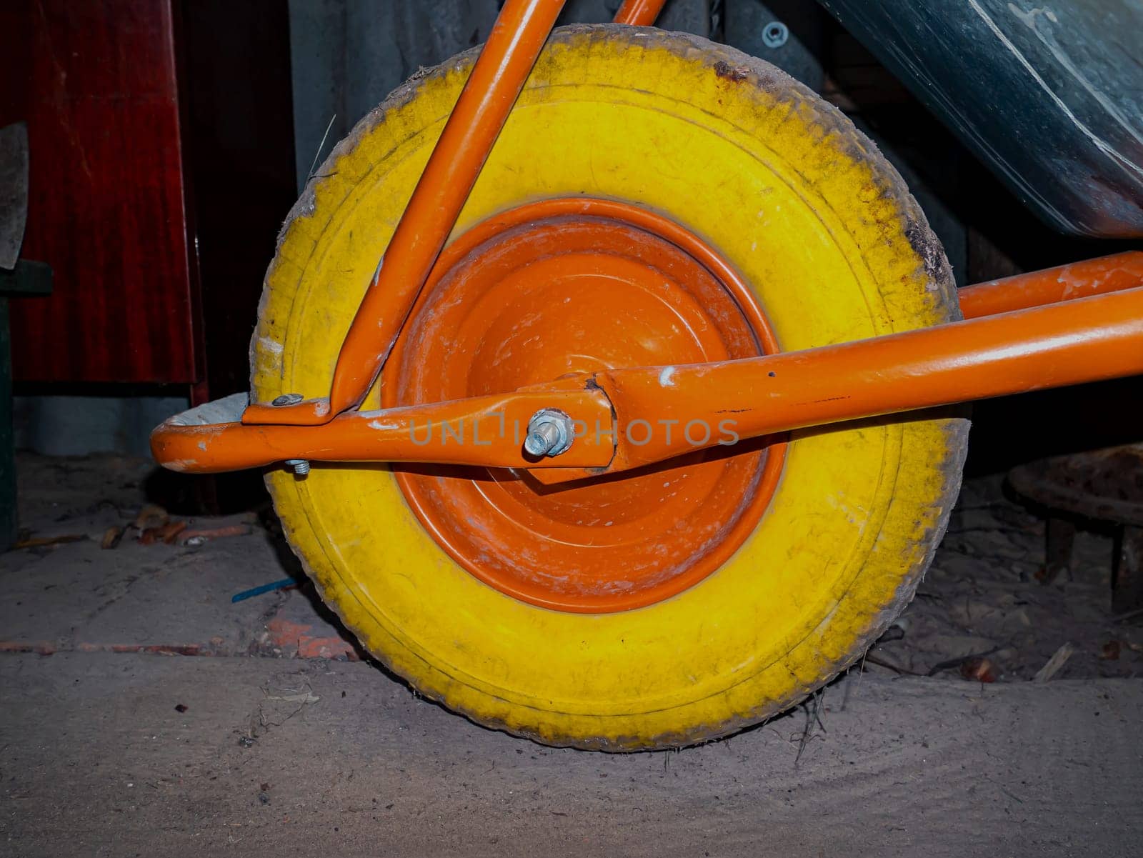 A yellow tire on a garden cart wheel. Orange disc on a yellow wheel. Garden wheelbarrow. Shipping. Kind of transport. Tire service. Background image. Place for text.