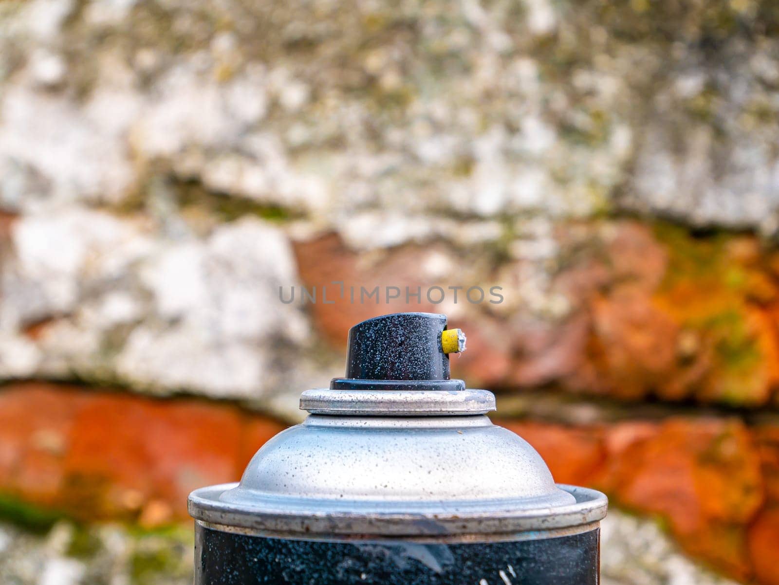 Black button of spray paint on a brick wall background. Aerosol spray paint. Graffiti on the walls. Building sector. Car painting. Push button mechanism. Spray. Background image. Place for text.