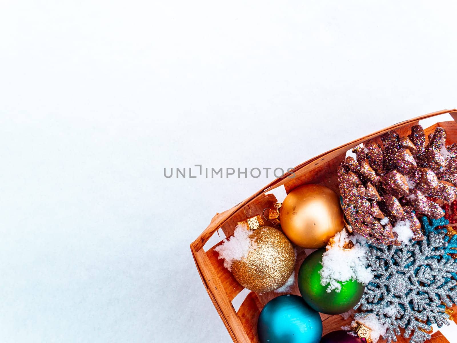 Christmas tree toys in a wooden box on white snow. Christmas holidays. New Year. Loose winter snow. New Years holidays. Winter vacation. Place for text. Greeting card. White background.