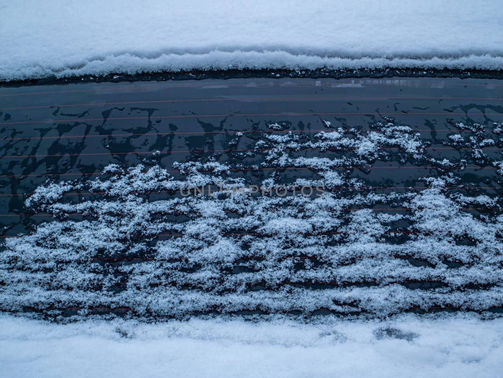 Melting snow on the car window glass. Car window glass. Snow melting. Water drops. Winter period. Frosty frost. Frozen water. Vehicle. Caring for a vehicle in winter. Background image.