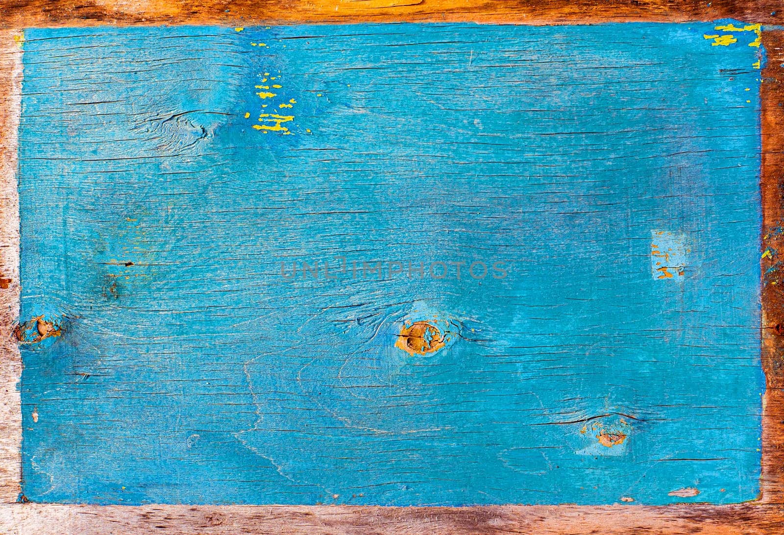 Faded texture of a wooden surface painted in blue. Peeling blue paint. Bough of a tree. Wood plywood texture. Aging process. Background image. Place for text. Cracks. Poster.