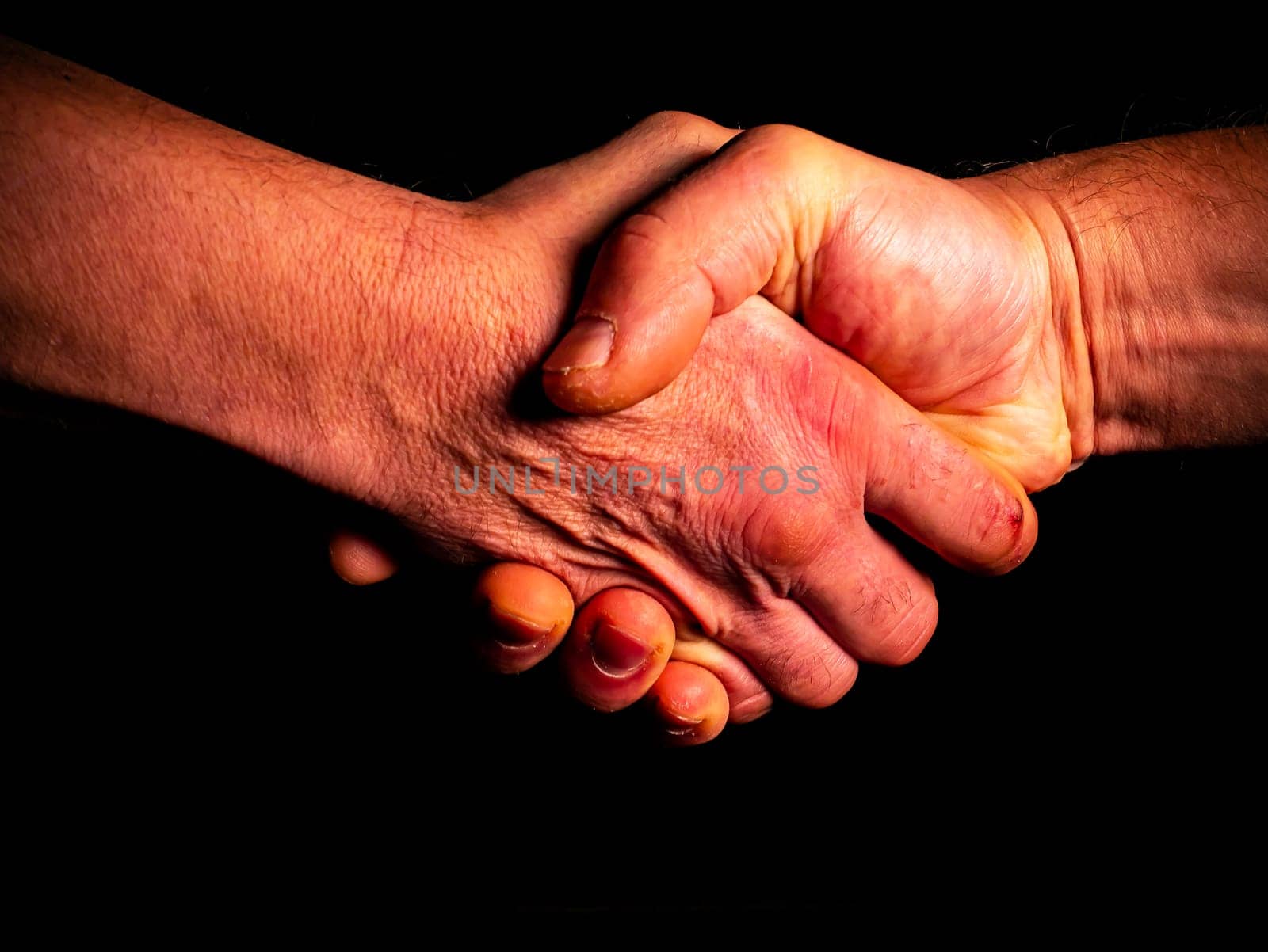 Greeting male handshake on black background at night. Male handshake. Greeting. Human hands. Palms of human hands. Black background. Confirmation of the agreement. Consent.