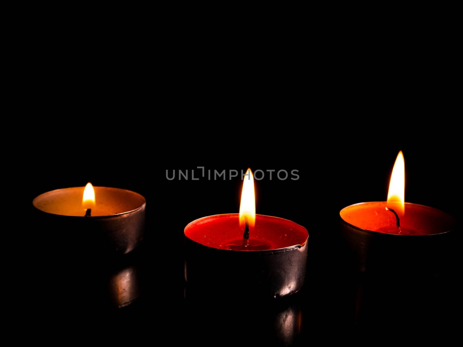 Flame of fire of burning wax candles on a black background. Wax candles. Flame of burning fire. Day of Remembrance. A minute of silence. Memorial Day. Place for your text. Background image.